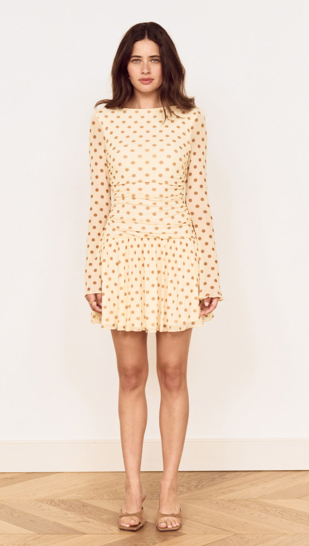 Butter Yellow Polka Dot Mini Dress with Drop Waist on a model, featuring long sleeves and a flared skirt.