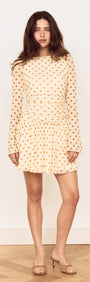 Butter Yellow Polka Dot Mini Dress with Drop Waist worn by a model, showcasing playful polka dots and a flared skirt.