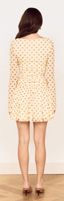 Back view of a Butter Yellow Polka Dot Mini Dress with Drop Waist featuring long sleeves and flared skirt.