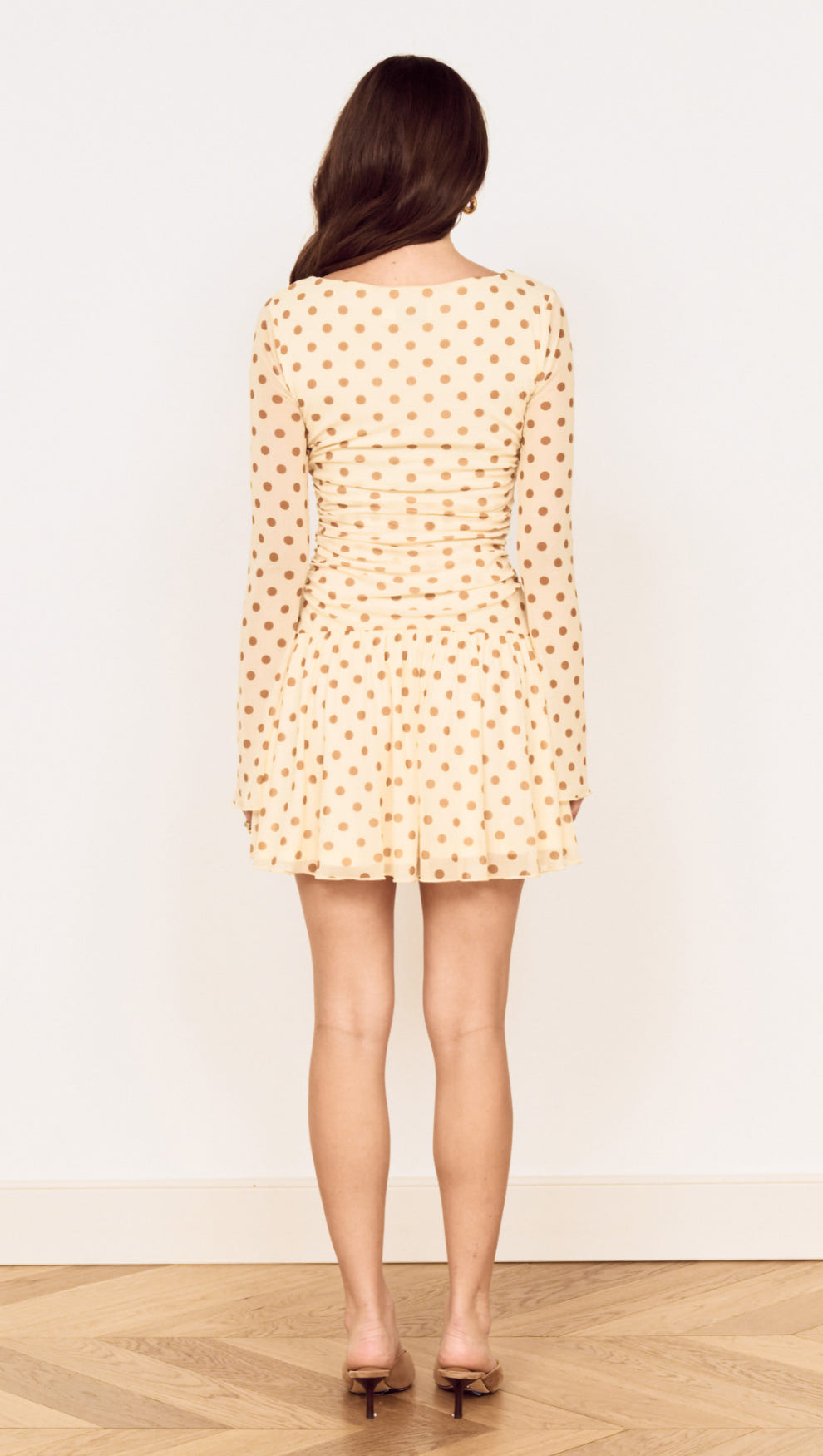 Back view of a Butter Yellow Polka Dot Mini Dress with Drop Waist featuring long sleeves and flared skirt.