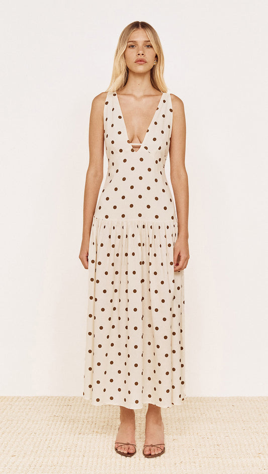 Model wearing a Drop Waist Midi Dress in Chocolate Spot with a plunging V-neckline and gathered skirt.