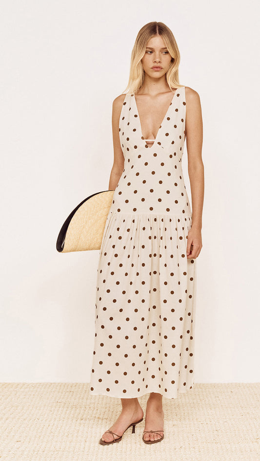 Model wearing Drop Waist Midi Dress in Chocolate Spot with a plunging neckline and gathered skirt.
