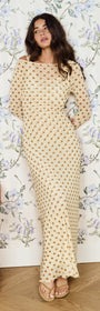 Butter Yellow Polka Dot Midi Dress on a model with floral wallpaper background, showcasing flared sleeves and a fitted silhouette.