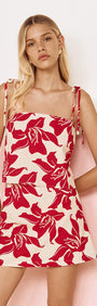 Cotton A-Line Mini Skirt in Red Floral worn by a model featuring a bold red floral print and adjustable straps.