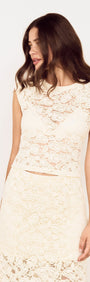 Woman wearing Cream Cotton Lace Micro Tee with floral lace detail and cap sleeves, styled for elegant occasion wear.