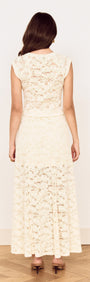 Back view of a woman wearing a Cream Cotton Lace Maxi Skirt with floral lace detailing and a flowing silhouette.