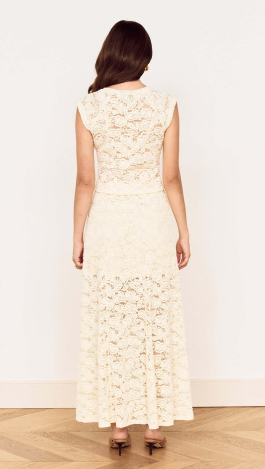 Back view of a woman wearing a Cream Cotton Lace Maxi Skirt with floral lace detailing and a flowing silhouette.