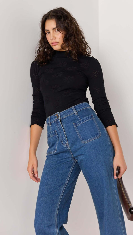 Model wearing high-waisted vintage blue bootcut jeans paired with a black long-sleeve top, showcasing a stylish retro look.