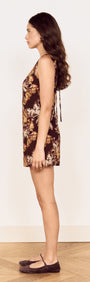 Side view of a model wearing a Brown Floral Tie Back Shift Dress showcasing its earthy floral print and open back detail.