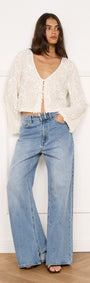 Model wearing Flute Sleeve Sequin Tie Blouse in Cream with wide-leg jeans, showcasing elegant eveningwear style.