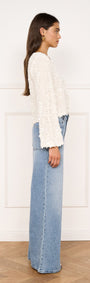 Flute Sleeve Sequin Tie Blouse in Cream styled with high-waisted jeans, showcasing a side view.