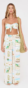 Woman wearing Island Postcard Knot Front Strapless Bikini Top with postcard-print pants and a bag.