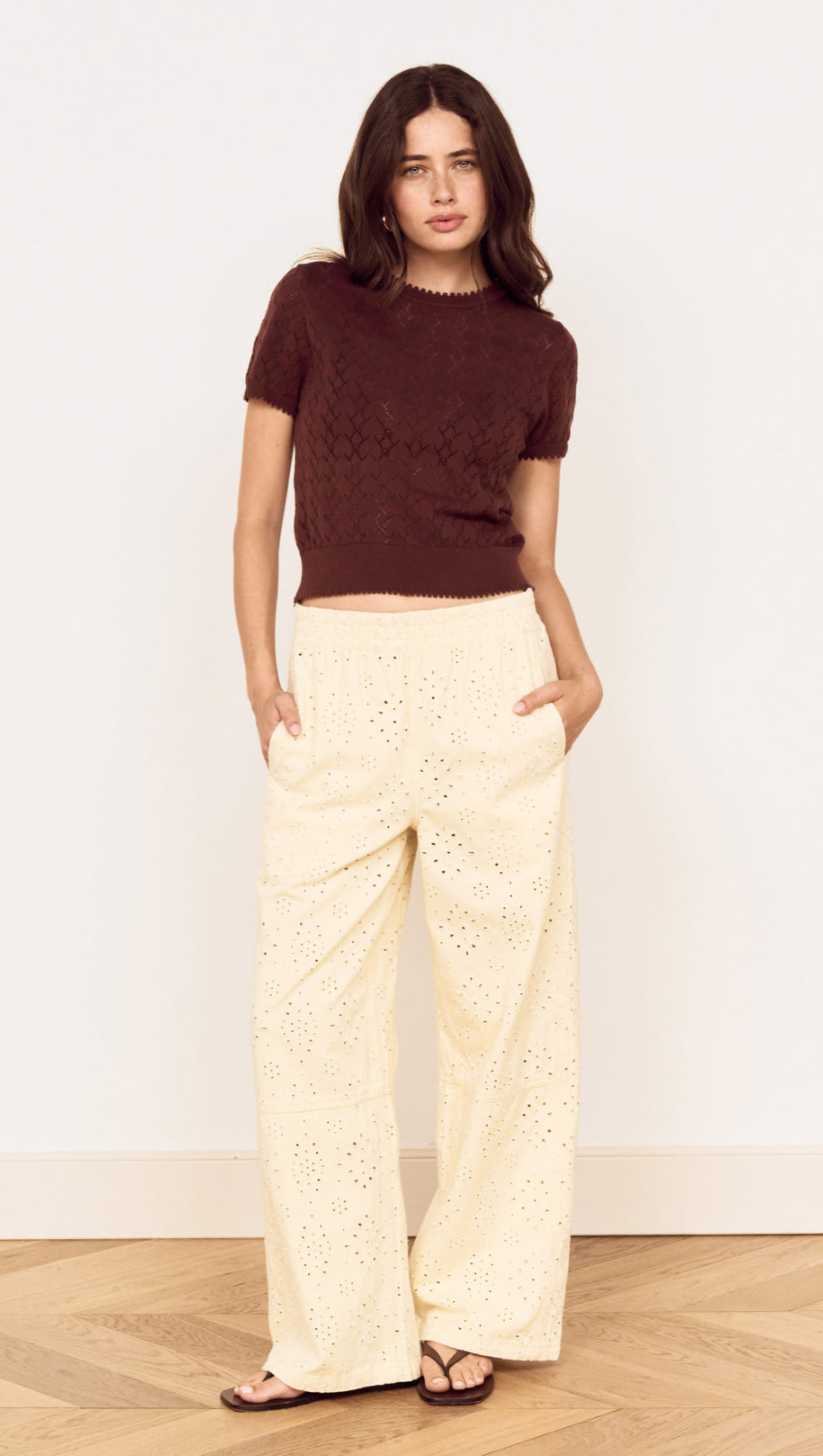 Model wearing a Brown Scallop Edge Knitted Tee with cream wide-leg pants, showcasing a chic and casual outfit.