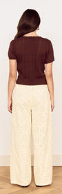 Back view of a model wearing a Brown Scallop Edge Knitted Tee with wide-leg eyelet trousers.