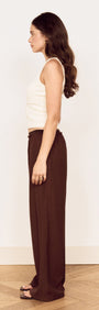 Side view of a model wearing a Cream Cotton Blend Tank with Lace Trim and brown wide-leg pants.