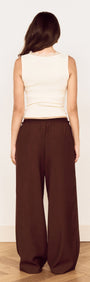 Back view of a woman wearing a Cream Cotton Blend Tank with Lace Trim and brown wide-leg pants.