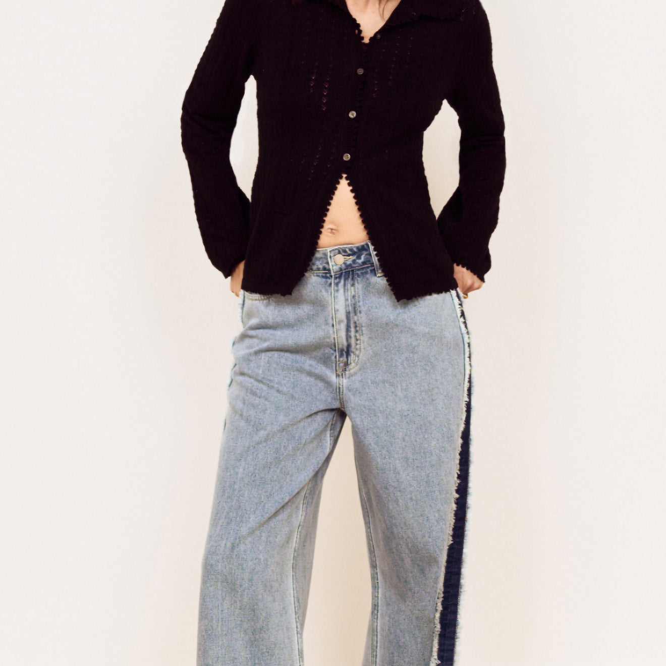 Model wearing a Black Scallop Edge Pointelle Cardigan paired with wide-leg jeans, showcasing a stylish casual look.