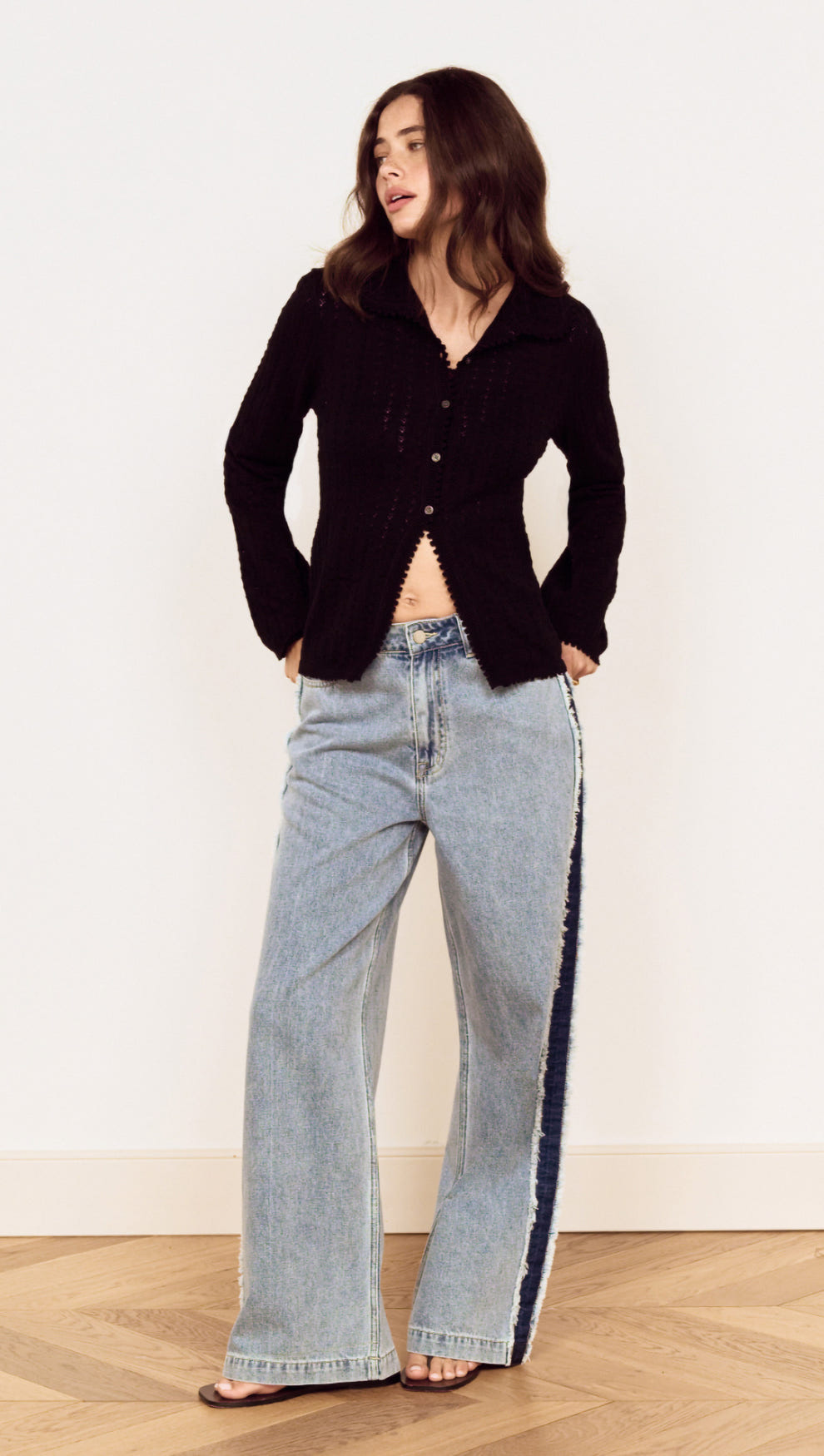 Model wearing a Black Scallop Edge Pointelle Cardigan paired with wide-leg jeans, showcasing a stylish casual look.