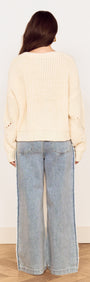 Back view of a woman wearing a Cream Round Neck Open Knit Jumper with relaxed jeans, showcasing chunky knit detail.