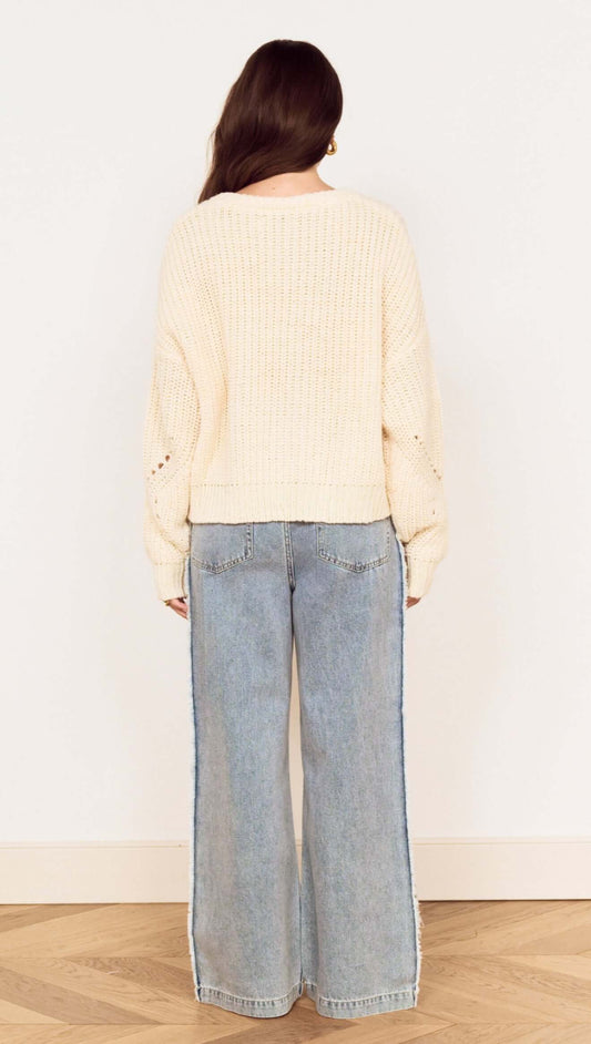 Back view of a woman wearing a Cream Round Neck Open Knit Jumper with relaxed jeans, showcasing chunky knit detail.