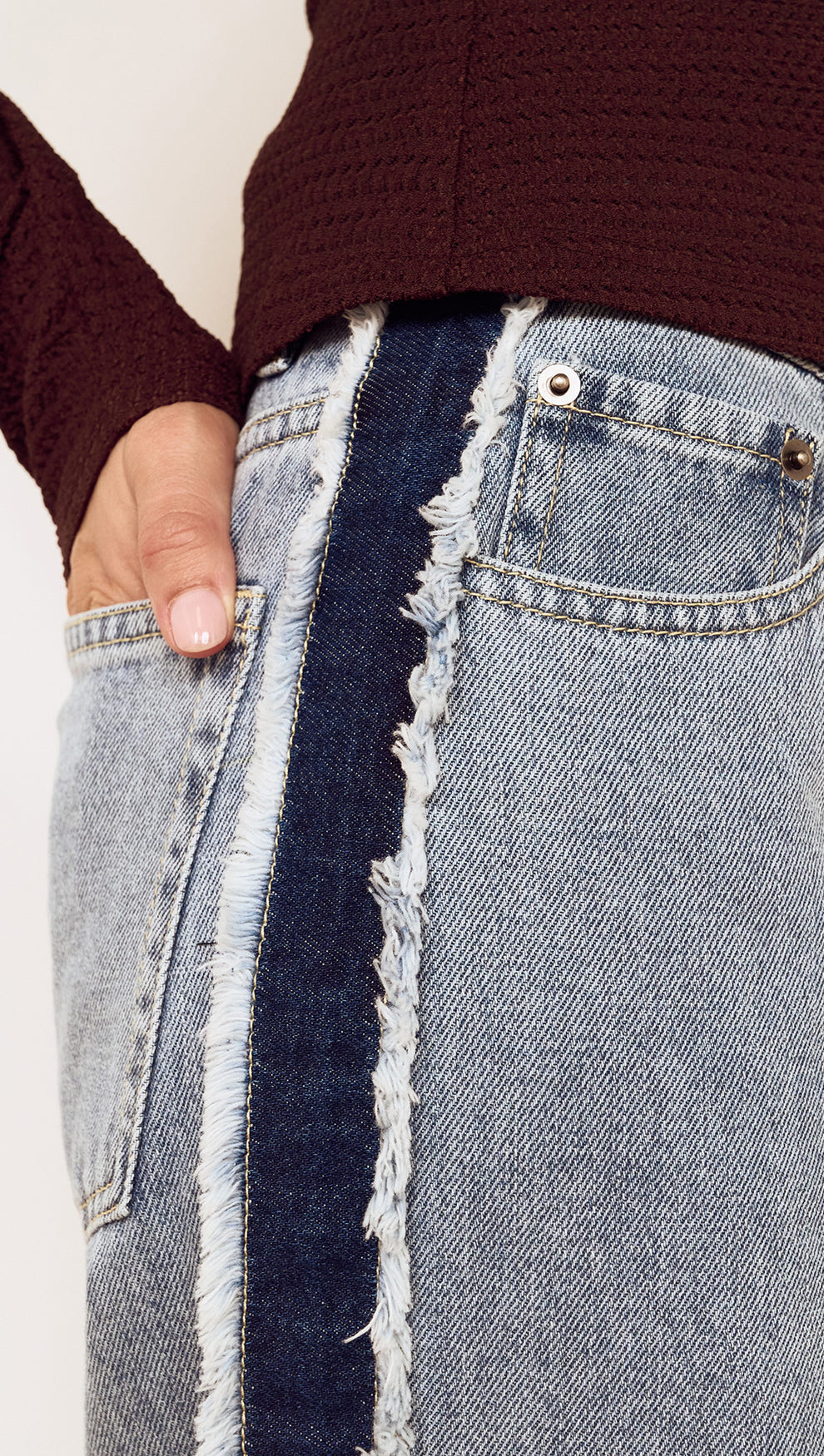 Close-up of Frayed Contrast Stripe Denim Jeans showcasing raw edge detailing and side panel contrast.