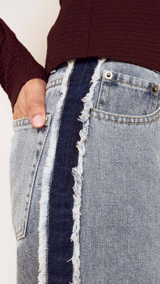Close-up of Frayed Contrast Stripe Denim Jeans showcasing raw edge detailing and side panel contrast.