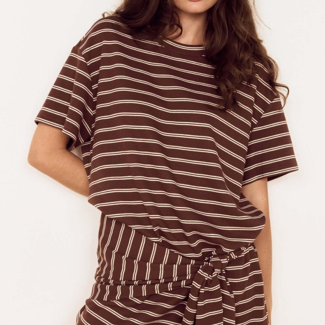 Model wearing Striped Tie Waist Jersey Mini Dress in chocolate stripe print, featuring an oversized tee bodice and fitted mini skirt.