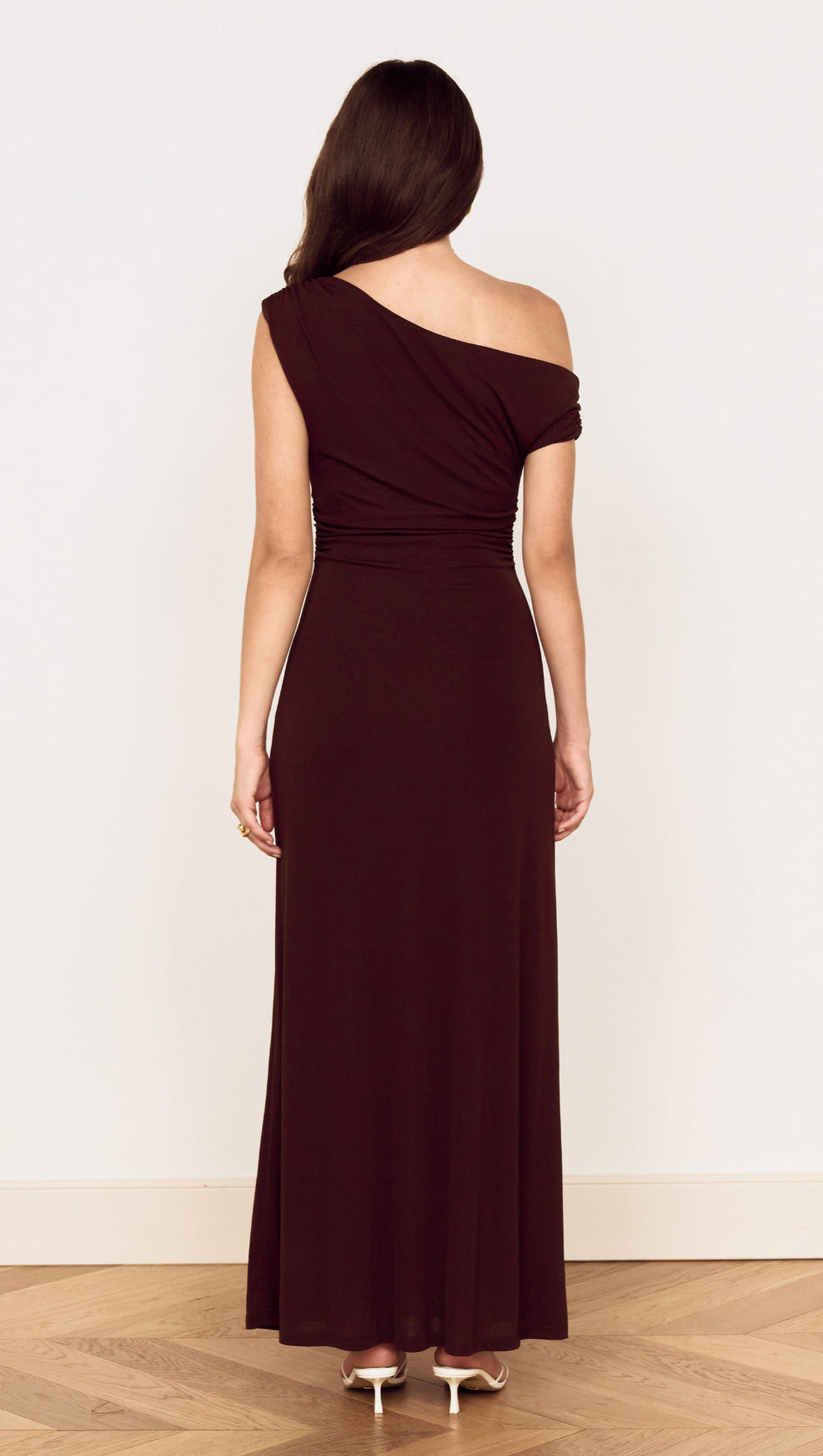 Rear view of a woman wearing a Chocolate One Shoulder Mesh Midi Dress with gathered detailing and fluid silhouette.