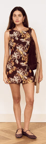 Model wearing a Brown Floral Tie Back Shift Dress with floral print and sleeveless design, complemented by a bag.