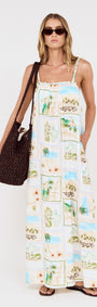 Model wearing Island Postcard Print Maxi Dress with Braided Straps, showcasing postcard-inspired print and braided shoulder straps.