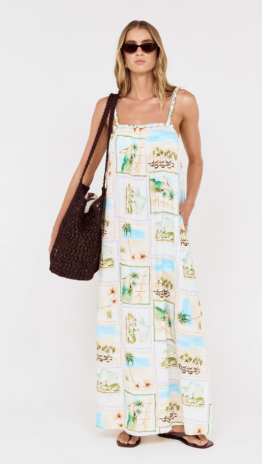 Model wearing Island Postcard Print Maxi Dress with Braided Straps, showcasing postcard-inspired print and braided shoulder straps.