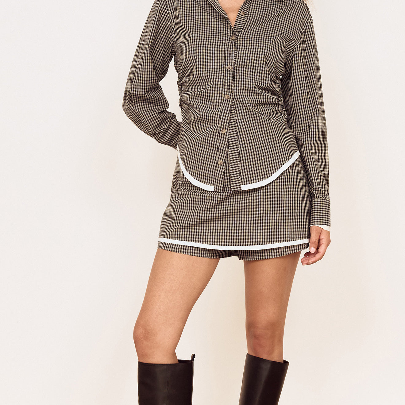 Model wearing the Contrast Hem Mini Skirt in Grey Check paired with a matching check shirt and knee-high boots.