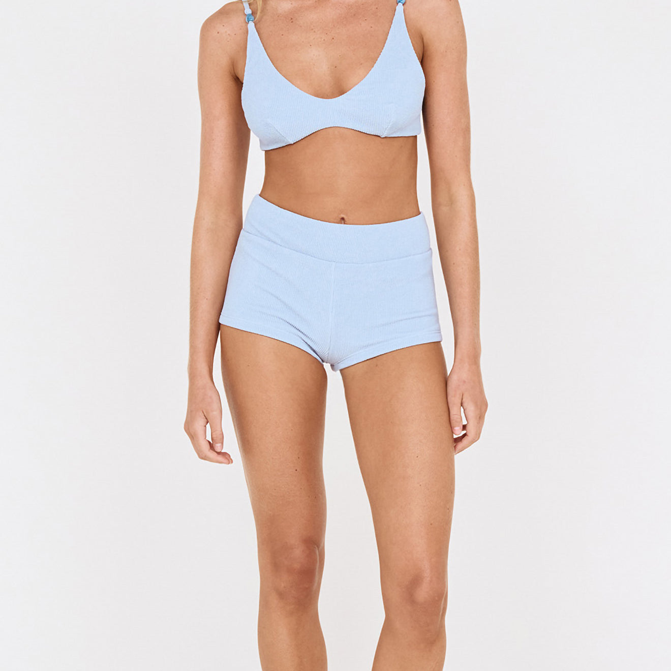 Model wearing textured swim shorts in sky blue and matching bikini top, ideal for beach days and poolside events.