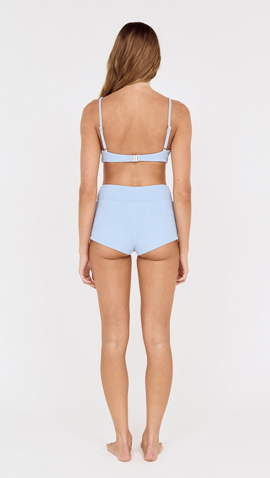 Back view of a model wearing Textured Swim Shorts in Sky Blue with a matching top.