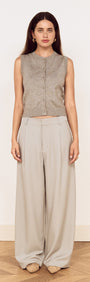 Model wearing a Round Neck Knitted Vest in Soft Grey with high-waisted light grey trousers, showcasing a minimalist style.