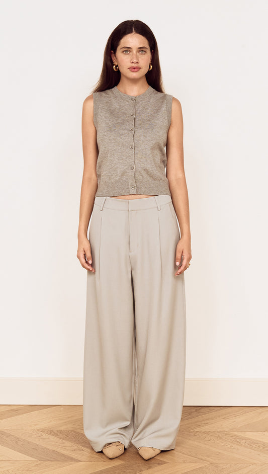 Model wearing a Round Neck Knitted Vest in Soft Grey with high-waisted light grey trousers, showcasing a minimalist style.