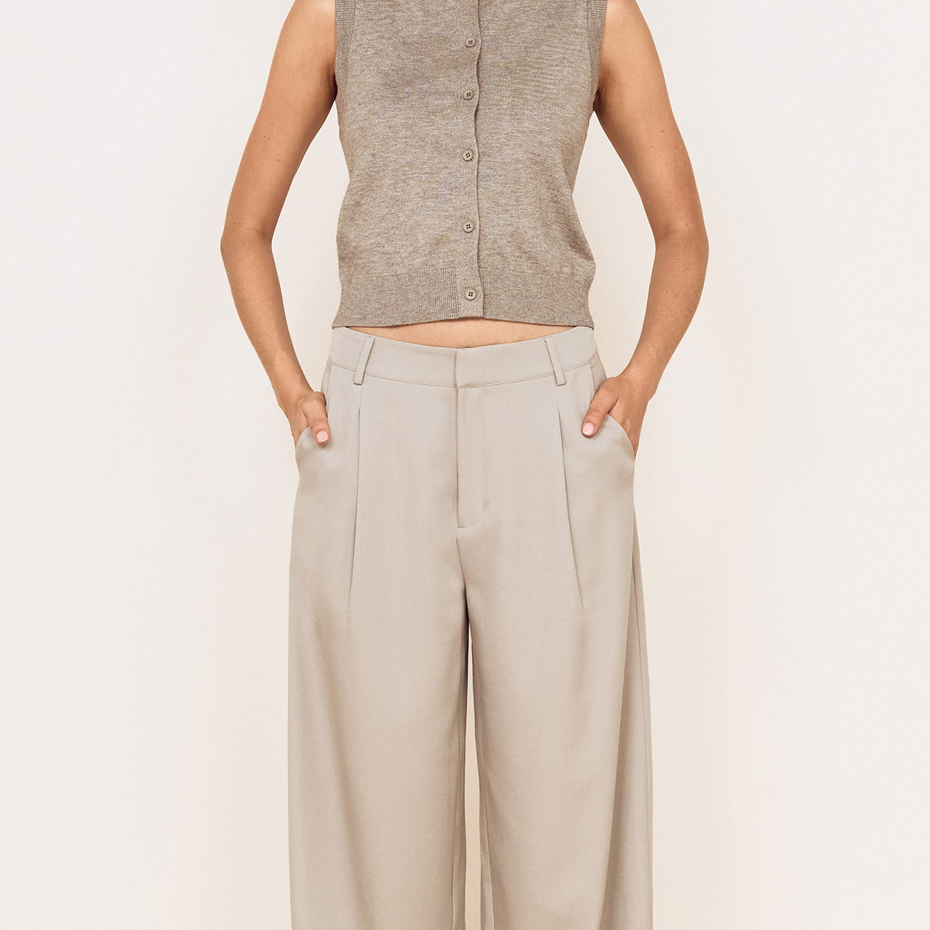 Model wearing Mid Rise Tailored Suit Pant in Grey with a grey sleeveless top, showcasing a relaxed and polished look.