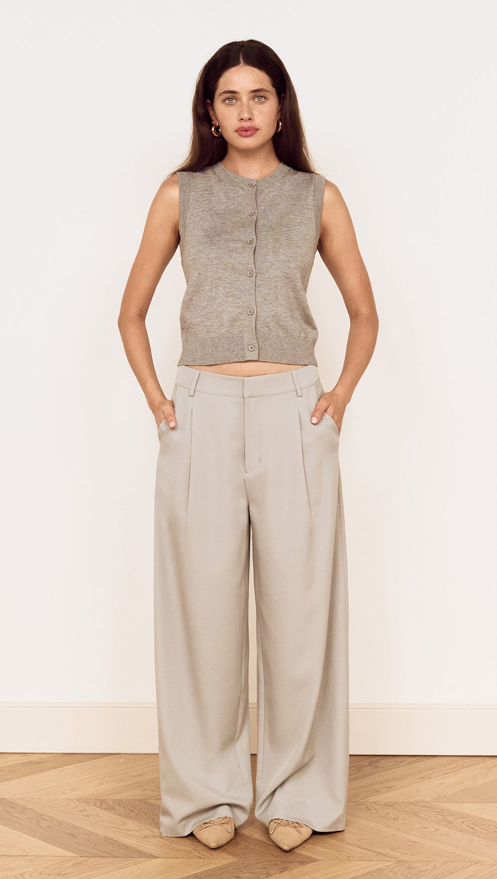 Model wearing Mid Rise Tailored Suit Pant in Grey with a grey sleeveless top, showcasing a relaxed and polished look.