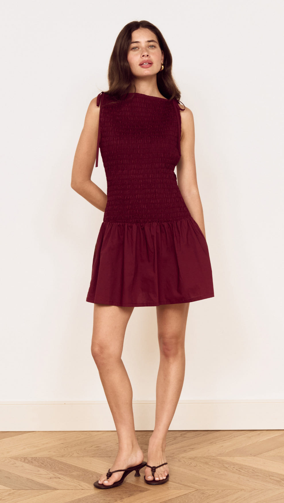 Model wearing a Cotton Shirred Mini Dress in Burgundy with a shirred bodice and gathered skirt.