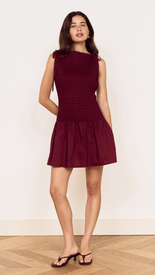Model wearing a Cotton Shirred Mini Dress in Burgundy with a shirred bodice and gathered skirt.