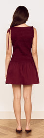 Back view of a woman wearing a Cotton Shirred Mini Dress in Burgundy with tie shoulder details.