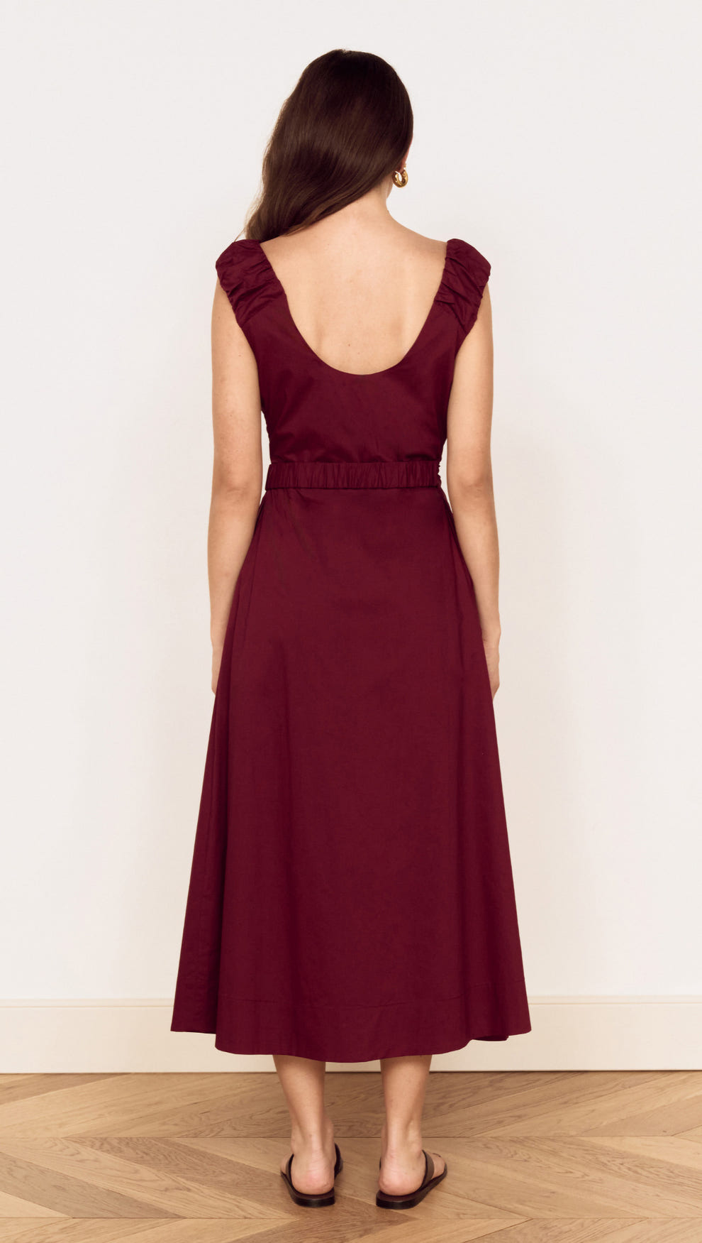 Back view of a woman wearing a Cotton Wrap Detail Midi Dress in Burgundy with ruffled sleeves and a belted waist.