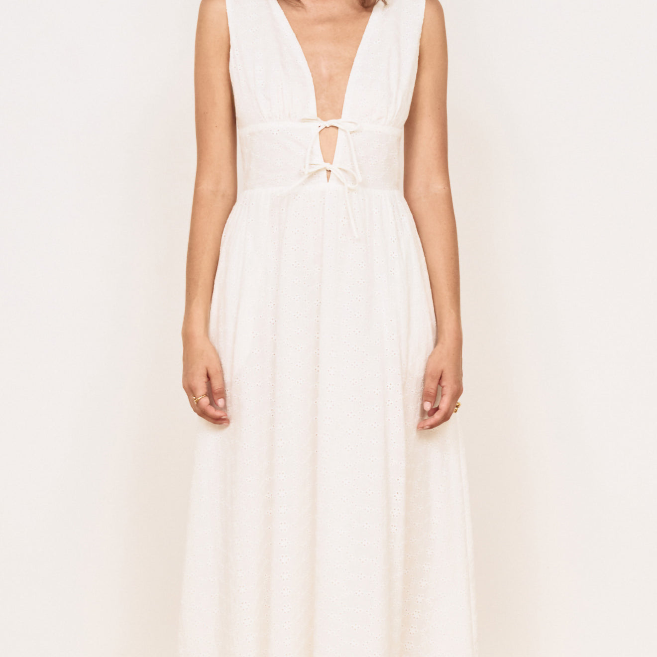 Cotton Broderie Anglaise Sleeveless Dress worn by a model, featuring a plunging V-neck and gathered skirt.