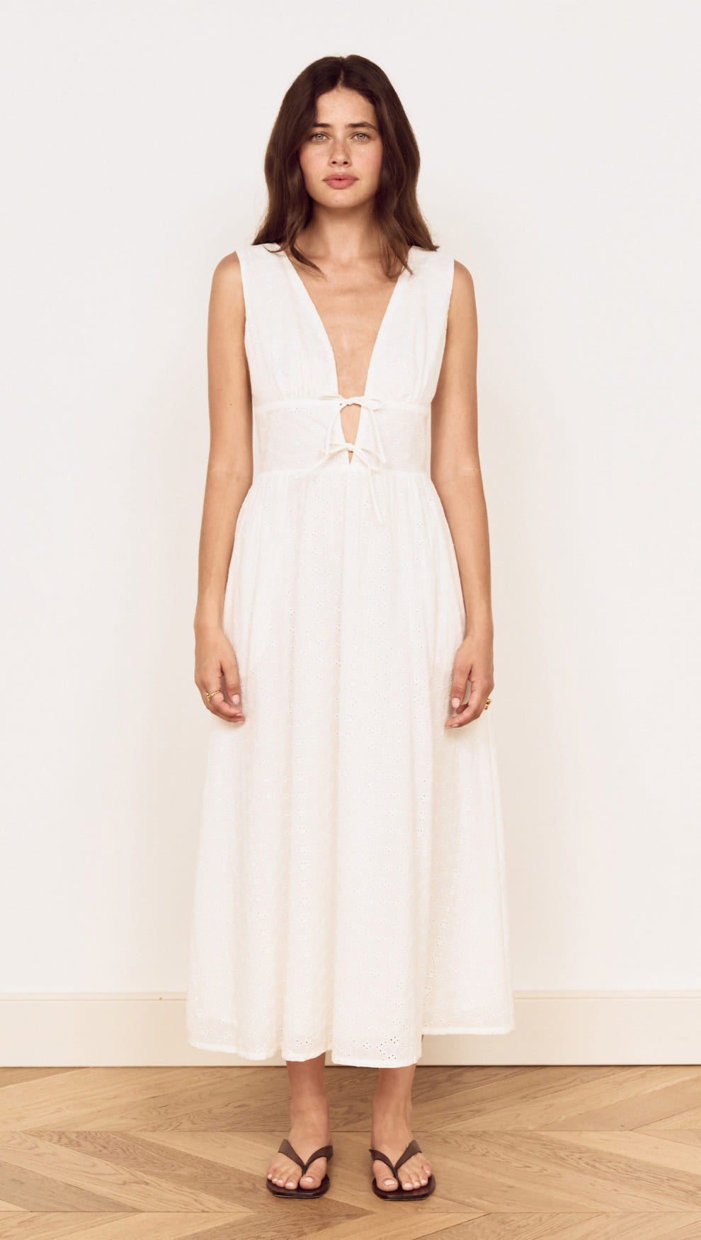 Cotton Broderie Anglaise Sleeveless Dress worn by a model, featuring a plunging V-neck and gathered skirt.