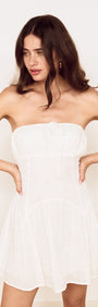 White Cotton Broderie Mini Dress model wearing strapless white dress with gathered bust and flared skirt.