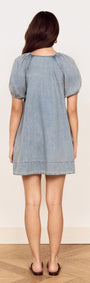 Back view of a woman wearing the Puff Sleeve Fluid Denim Mini Dress in soft washed denim.
