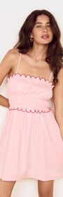 Model wearing a Linen Blend Mini Dress with Scallop Detail in soft pink, showcasing gathered bodice and scalloped embroidery.