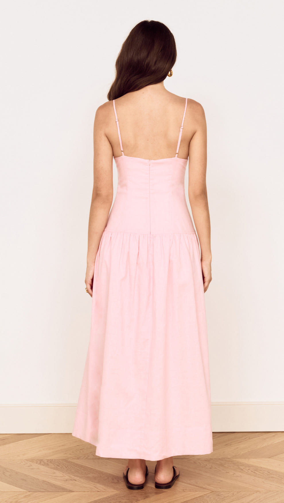 Back view of a woman wearing a Linen Blend Midi Dress with Drop Waist in soft pink, showcasing its elegant design.