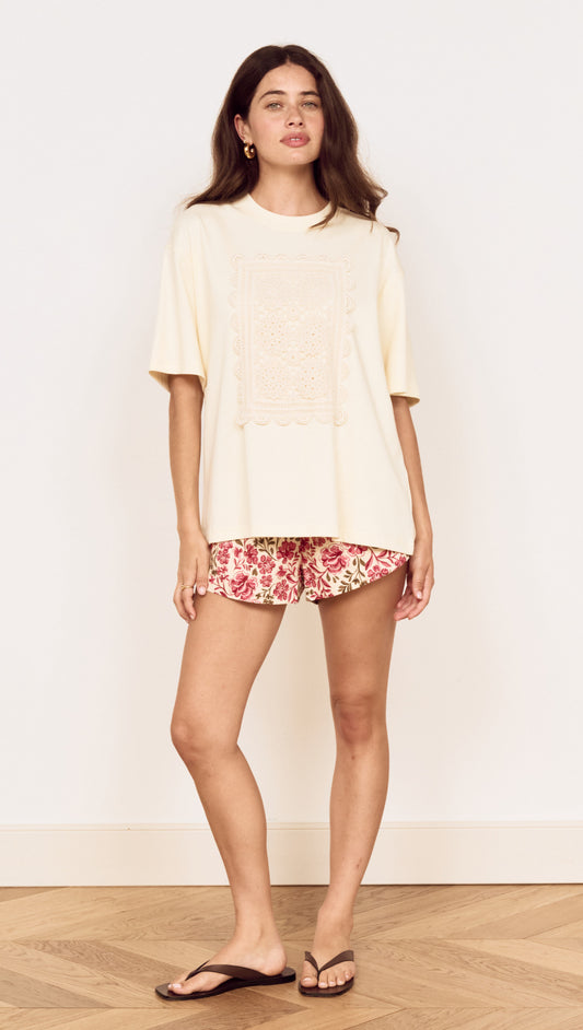 Model wearing Crochet Detail Oversized T Shirt with crochet applique panel, paired with floral shorts.