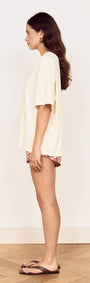 Model showcasing the Crochet Detail Oversized T Shirt from the side, highlighting its relaxed fit and soft cream color.